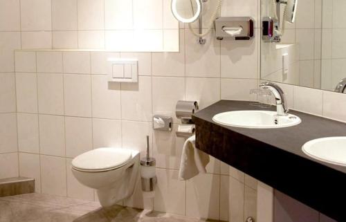 a white bathroom with a toilet and a sink at Gasthof zur Post Oberwirt in Chieming