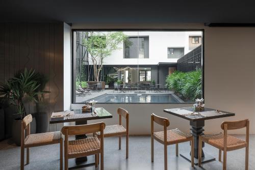 a room with a table and chairs and a pool at Lilit Bang Lumphu Hotel in Bangkok