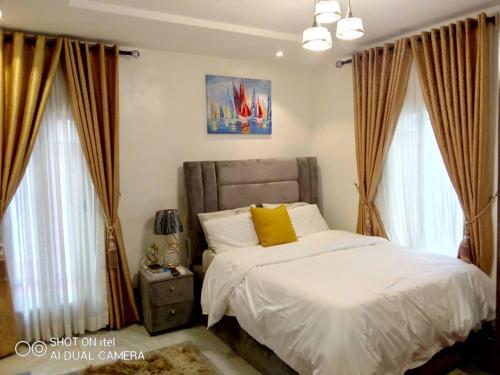 a bedroom with a bed with white sheets and yellow pillows at HOMEDALES Freedom Way LEKKI Phase1 LAGOS in Lekki