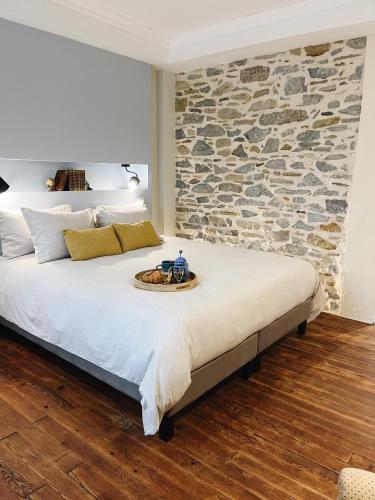 une chambre avec un grand lit avec un mur en pierre dans l'établissement Domaine Labouroume, à Salies-de-Béarn