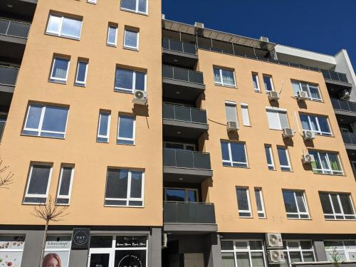 a tall yellow building with windows at Welcome Stara Zagora Apartment 4 Guests Pet Friendly in Stara Zagora