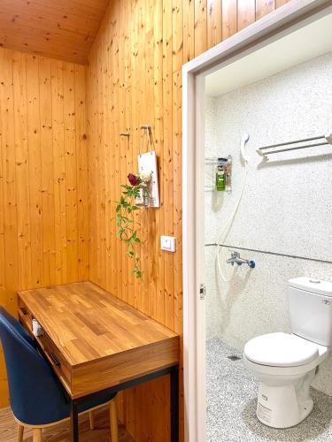 łazienka z toaletą i drewnianą ścianą w obiekcie Temu 鐵木蘭農場 w mieście Gauyi