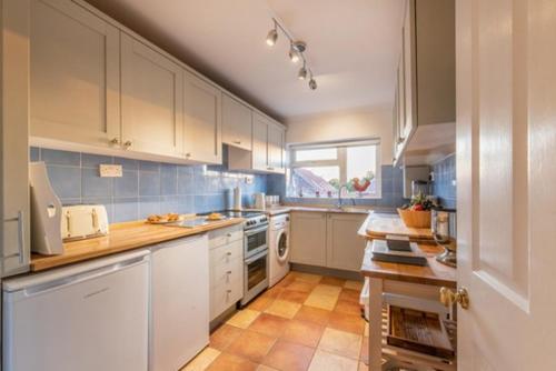 a large kitchen with white cabinets and blue tiles at Glastonbury, large House Stunning views 2 to 5 bedrooms, 3 receptions turn into bedrooms in Glastonbury