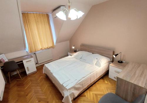a bedroom with a large white bed and a desk at Thermal Hotel in Komárom