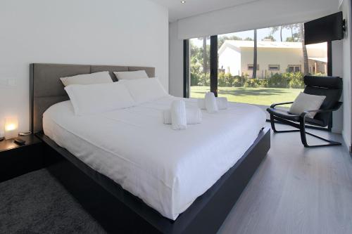 a bedroom with a large white bed and a chair at Villa Alfazema IV in Aroeira