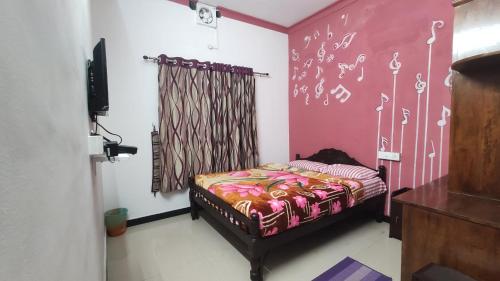 a bedroom with a bed and a pink wall at Gokulam Holiday Home in Munnar