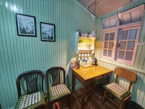 um quarto com uma mesa de madeira e 2 cadeiras e uma mesa e cadeira em Basnet Apartment em Darjeeling