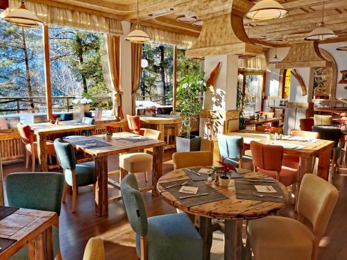 ブレッドにあるRibno Alpine Hotelの木製のテーブルと椅子と窓のあるレストラン