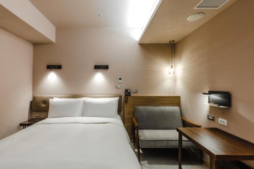 a bedroom with a bed and a desk and a chair at Inns Hotel in Kaohsiung