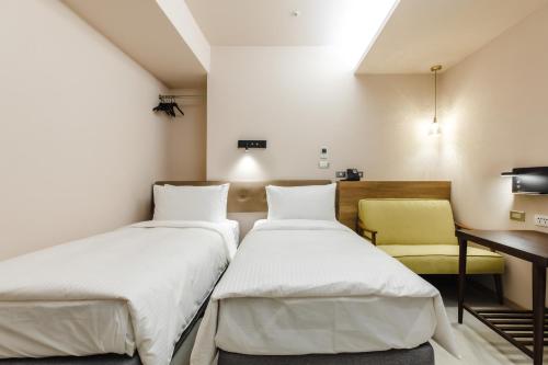 two beds in a room with a desk and a chair at Inns Hotel in Kaohsiung