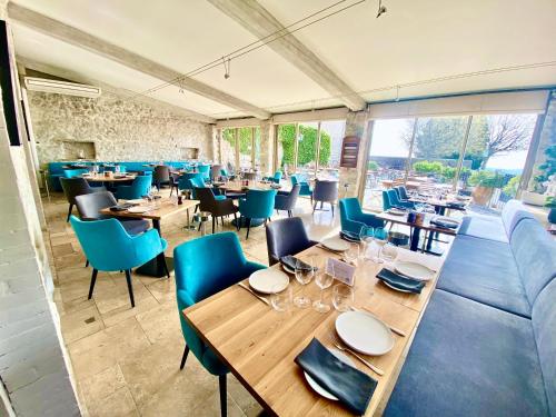 a restaurant with wooden tables and blue chairs at Auberge du Vieux Château in Cabris