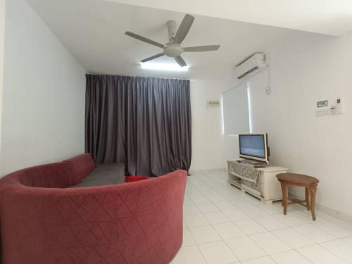 a living room with a red couch and a television at Khaleesi Afamosa Residency Homestay in Kampong Alor Gajah