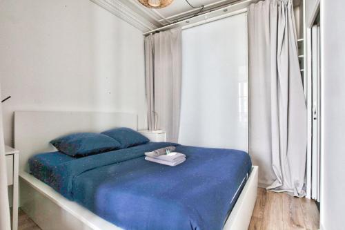 ein Schlafzimmer mit einem blauen Bett mit blauen Kissen in der Unterkunft Appartement Quartier Hotel de Ville in Paris