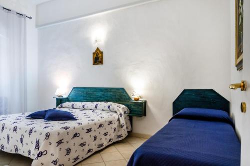 twee bedden in een kamer met witte muren bij Palmiro in Castiglione della Pescaia