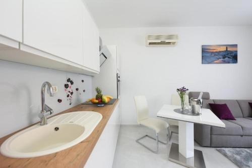 eine Küche mit einem Waschbecken und ein Wohnzimmer mit einem Sofa in der Unterkunft Apartment Lant in Zadar