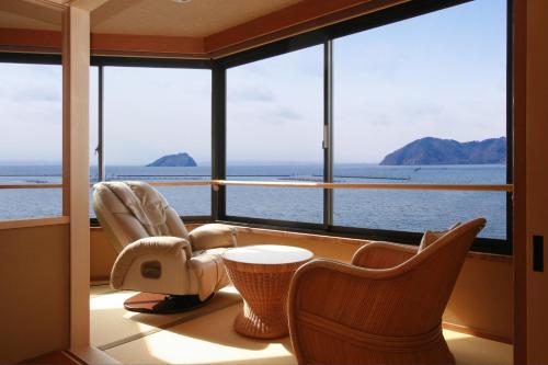 a room with a large window with chairs and a table at Ryokan Beniayu in Nagahama