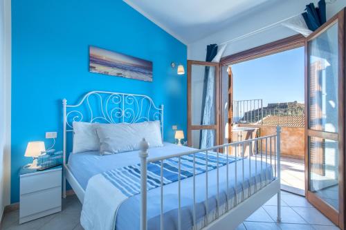 a blue bedroom with a bed and a balcony at Attico Castelsardo con vista mare in Castelsardo