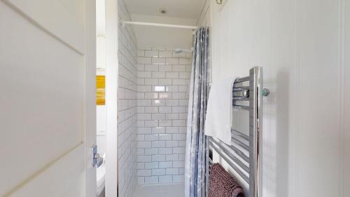 ein Bad mit einer Dusche und einer weiß gefliesten Wand in der Unterkunft F17 Up-A-Bank, Riviere Towans in Hayle