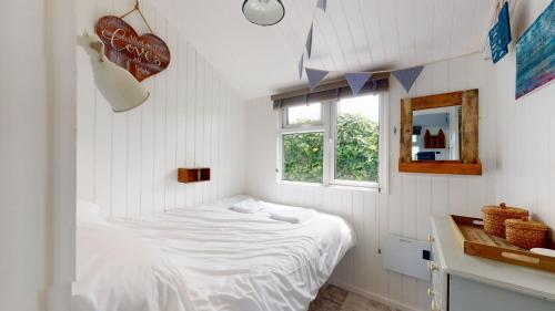 ein weißes Schlafzimmer mit einem Bett und einem Fenster in der Unterkunft F17 Up-A-Bank, Riviere Towans in Hayle