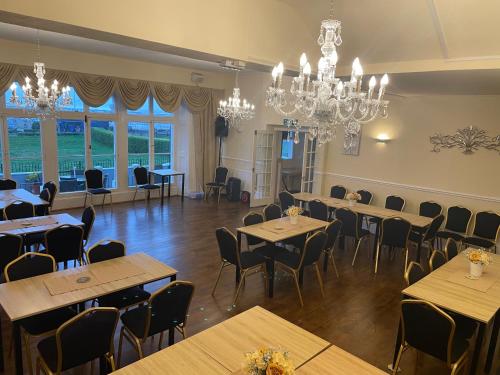 uma sala de jantar com mesas e cadeiras e um lustre em Royal Grosvenor Hotel em Weston-super-Mare