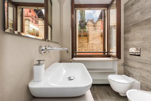 een badkamer met een wastafel, een toilet en een raam bij Flats4rent Luca in Verona
