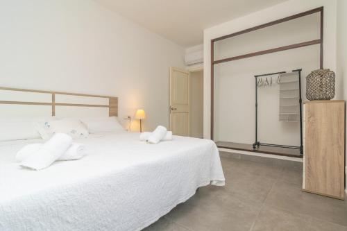 a bedroom with a large white bed and a closet at Cala Rafalino in S'Illot