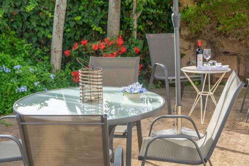 an outdoor table and chairs with a glass table and a bottle of wine at Cala Rafalino in S'Illot