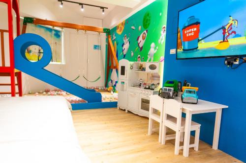 a childs room with a toy kitchen and a blue wall at 寶貝樂溜滑梯親子民宿 in Luodong