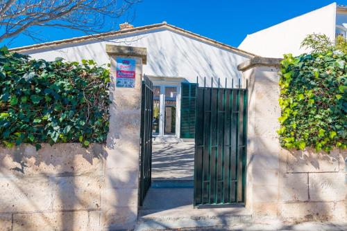 a white house with a green gate at Cala Rafalino in S'Illot
