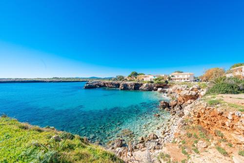 a view of a beach with blue water and houses at Cala Rafalino in S'Illot