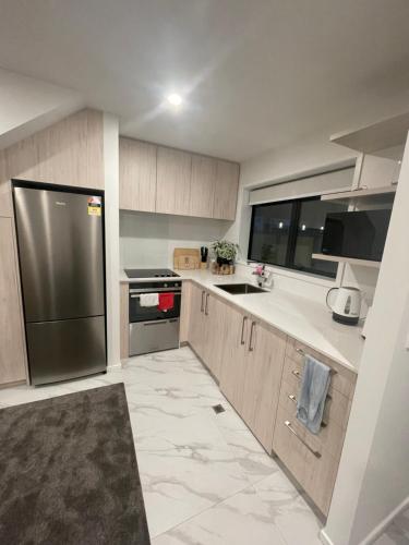 a kitchen with a stainless steel refrigerator and cabinets at A Hidden Gem near Hagley park in central city in Christchurch