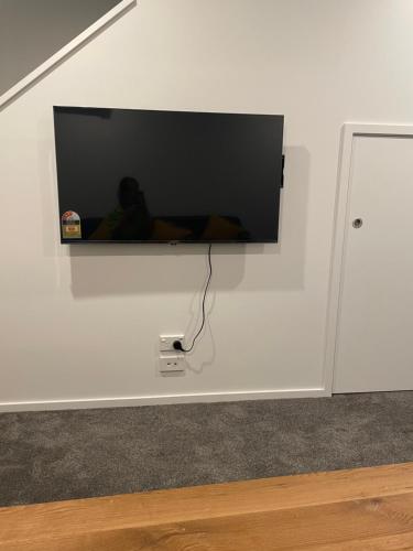 a flat screen tv hanging on a white wall at A Hidden Gem near Hagley park in central city in Christchurch