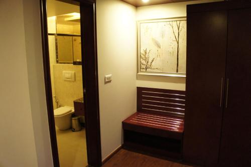 a bathroom with a bench and a window and a toilet at Bravura Gold Resort in Meerut