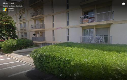 un bâtiment avec une haie verte devant lui dans l'établissement Studio avec balcon et climatisation, à Balaruc-les-Bains