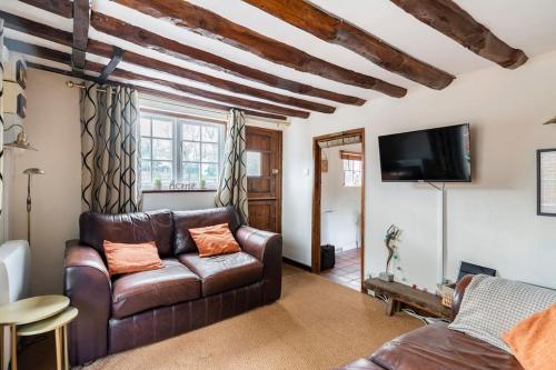 a living room with a leather couch and a tv at Annex to Berry Cottage 2 Bedroom Cottage in Bramfield