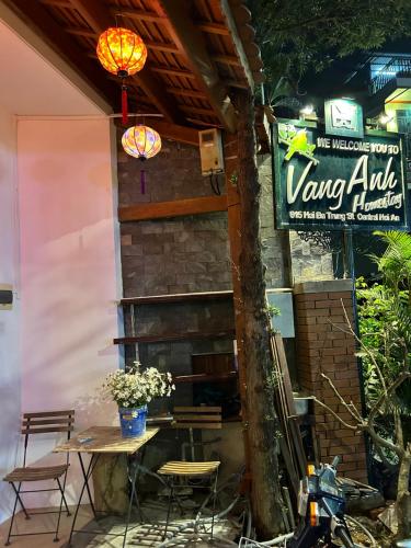 a patio with a table and chairs and a sign at Vang Anh Homestay Hoi An in Hoi An