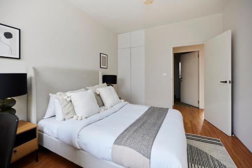 a white bedroom with a large bed with white pillows at The Southwark Wonder - Charming 1BDR Flat with Patio in London