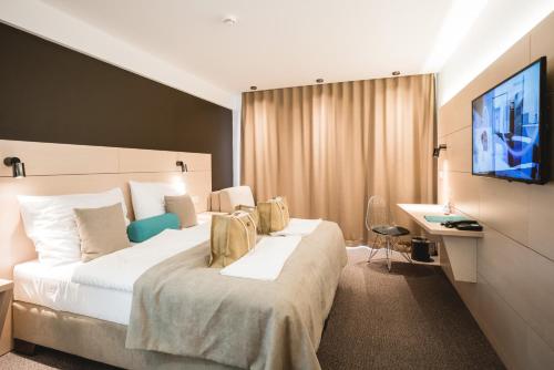 um quarto de hotel com uma cama grande e uma televisão em Hotel Thermal ŠÍRAVA em Kaluža