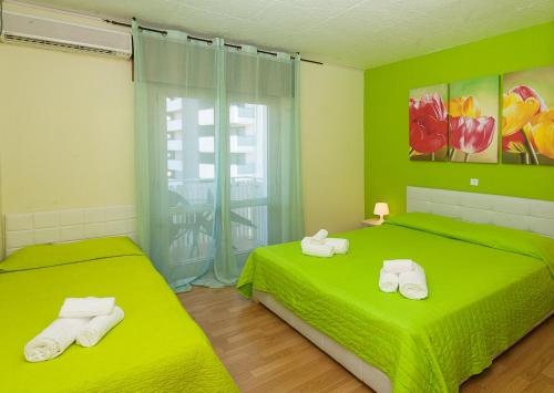 two beds in a room with green walls at Hotel Romantik & Depandance in Lignano Sabbiadoro