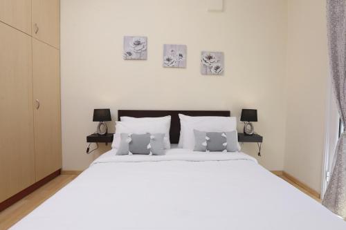 a bedroom with a large white bed with three pictures on the wall at Tranquil Apartments Corfu in Kontokali