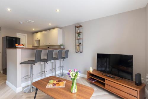 uma sala de estar com uma televisão de ecrã plano e uma mesa em Elliot Oliver - 2 Bedroom Garden Apartment With Parking em Cheltenham