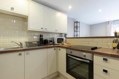 een keuken met witte kasten en een wastafel bij Elliot Oliver - 2 Bedroom Garden Apartment With Parking in Cheltenham