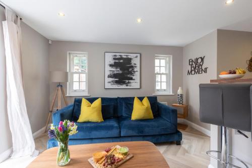 a blue couch in a living room with yellow pillows at Elliot Oliver - 2 Bedroom Garden Apartment With Parking in Cheltenham