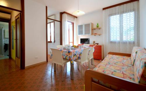 a dining room with a table and chairs and a living room at Appartamenti Cocai, Acquaverde in Bibione