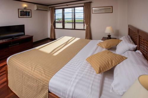 a bedroom with a large bed and a flat screen tv at Lao Orchid Hotel in Vientiane