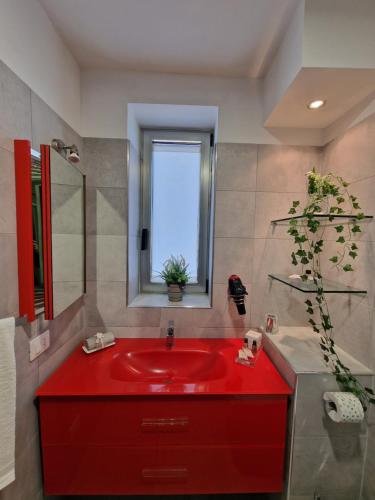 lavabo rojo en un baño con ventana en Residence Hotel Margherita, en Montalto di Castro