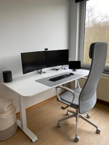 escritorio blanco con monitor de ordenador y silla en Cosy Apartment near Antwerp, en Mortsel