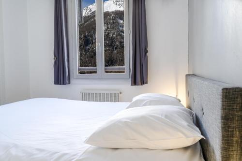 a bedroom with a bed with white sheets and a window at Les Anémones 6 places in Les Orres