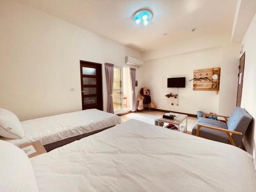 a hotel room with two beds and a tv at Xinzhan 23 B&B in Taitung City