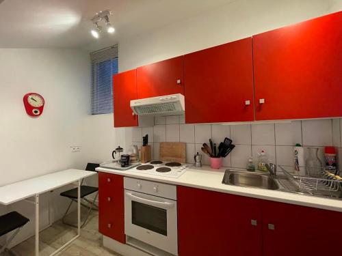 een keuken met rode kasten en een fornuis met oven bij L'appartement à la campagne in Vermenton